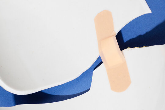 Conceptual image of healing: broken surface fixed with plaster bandaid
