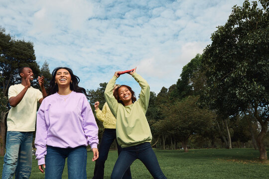 Diverse friends laughing and playing games in park