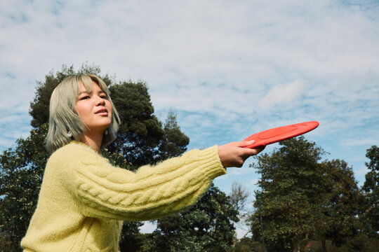 Young woman playing frisbee enjoying outdoor park activity