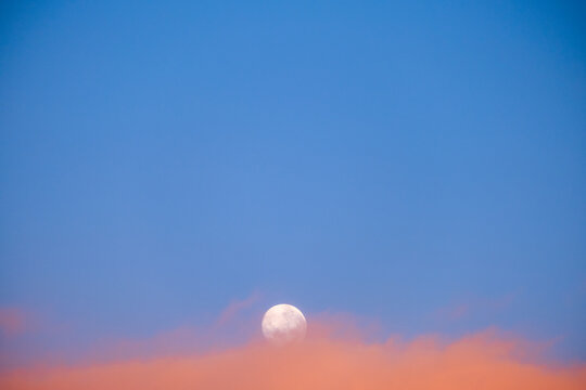 Moon Rising Over Sunset Clouds