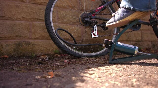 Cyclist pumping flat tyre on bicycle