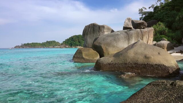 View of Similan Islands featuring large granite boulders, turquoise water, and lush tropical vegetation along the coastline in Lam Kaen, Phang Nga, Thailand.