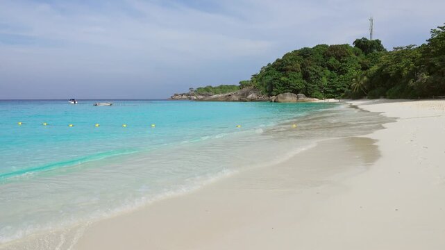 View of Similan Islands beach with turquoise water, white sand, and lush green vegetation in Lam Kaen, Phang Nga, Thailand.