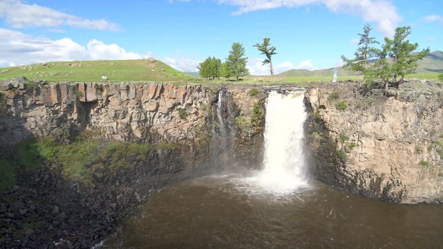 Orkhon waterfall drops through volcanic rock in Mongolia, scenic cascade within steppe landscape.