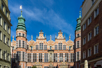 Fototapeta premium Great Armoury building in Gdansk featuring ornate Dutch Mannerist facade details, showcasing its historic significance and architectural beauty under a clear blue sky