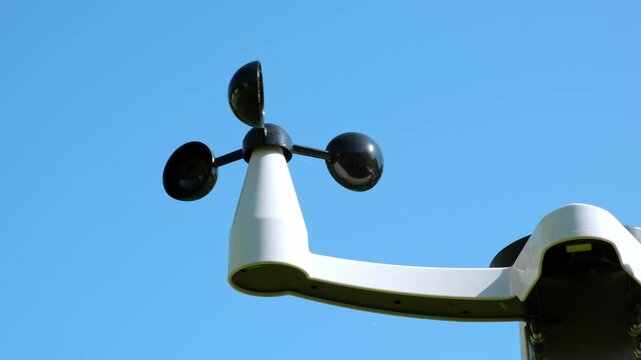The Anemometer measuring wind speed outdoors on a blue sky background. Weather monitoring, meteorological equipment, climate study. Modern wireless weather station. Smart home technology. HQ 4K.