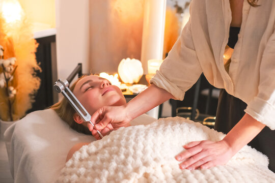 Woman receiving tuning fork sound therapy during a holistic wellness session, representing neurowellness, nervous system regulation, sensory relaxation and restorative self care.