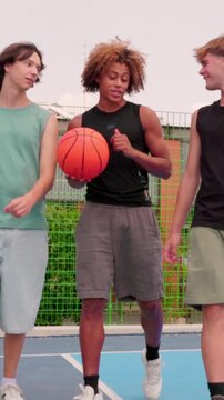vertical Multicultural friends laughing together on a basketball court