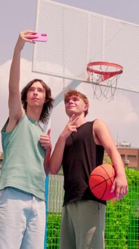 vertical Young men taking a selfie at an outdoor basketball court