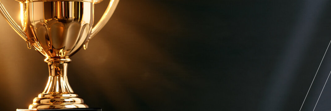 Goldener Pokal mit Lichtstrahlen vor dunklem Hintergrund