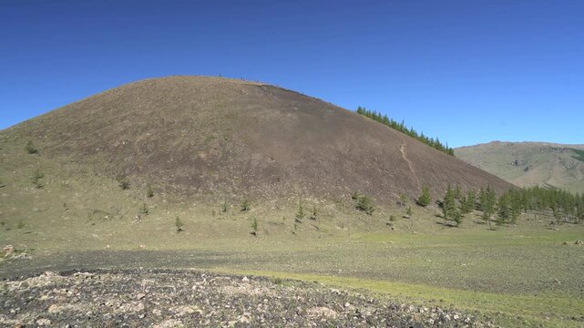Basalt volcanic hill rises above rugged terrain, revealing tuff and tuffite formations.