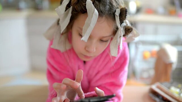 Little beautiful girl plays on her mobile phone