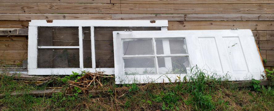 Discarded Vintage Doors Leaning Against a Wooden Fence