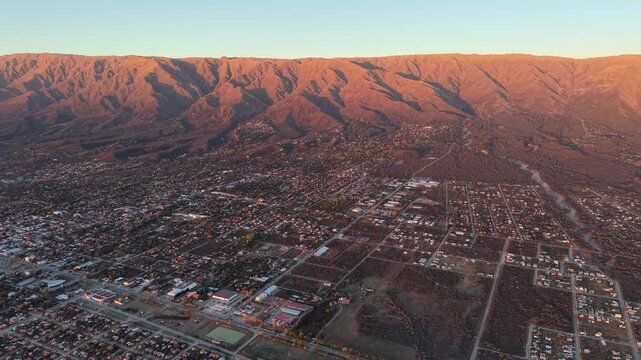 Aerial stock footage of Villa de Merlo town and Comechingones mountains at golden hour