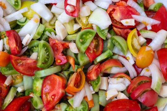 Full frame texture of freshly chopped salad with red and green tomatoes and onions. Close-up detailed background of organic sliced vegetables, healthy eating and vegan food concept