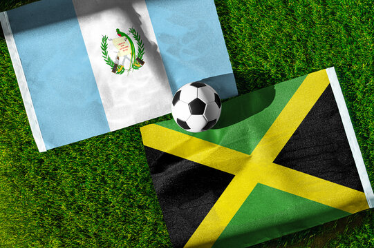 Guatemala vs. Jamaica football match. National flags on green grass with soccer ball in the middle. Football background for international match.