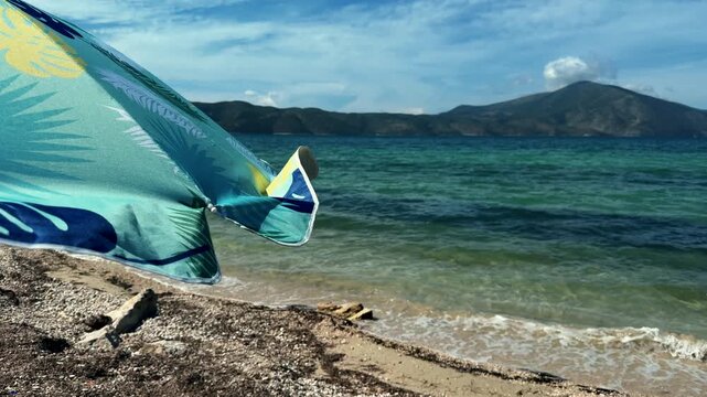 Beach Parasol Edge Swaying On Coastline With Turquoise Sea Water And Mountains. Vacation Travel Destination
