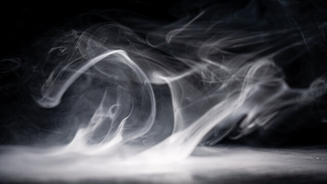 Smoke rising in the dark with an unclear shape forming, creating an abstract scene in a minimal light setting