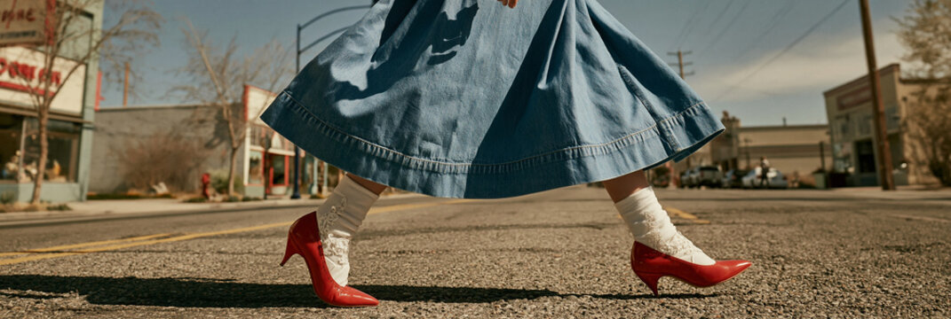 Frau in blauem Jeanskleid und roten Schuhen auf der Stra&szlig;e