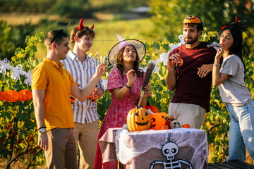 Obraz premium Friends enjoying a Halloween celebration together in a sunny vineyard.
