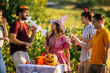 Obraz premium Young adults chatting and celebrating Halloween at an outdoor vineyard party.