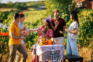 Obraz premium Group of friends laughing out loud during a Halloween party in a vineyard.