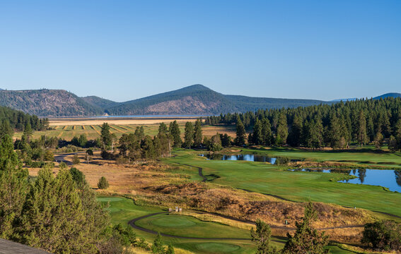 Manicured fairways of a golf course meet natural grasslands and a distant lake framed by forested mountains in Klamath Falls Oregon.