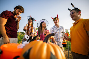 Obraz premium Low angle view of young people wearing Halloween accessories having fun at an outdoor event.