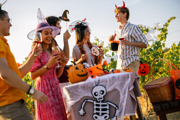 Obraz premium Cheerful young people enjoying drinks and conversation at an outdoor Halloween party.