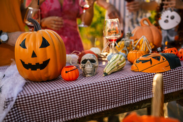 Obraz premium Close-up of a Halloween party table decorated with jack-o-lantern pumpkins, skulls, and wine glasses.