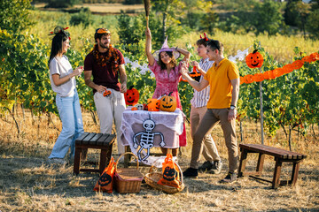 Obraz premium Full length view of friends celebrating Halloween party in a sunny autumn vineyard.