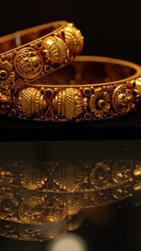 Intricate gold bangles with red gemstone accents displaying ornate metal textures in this luxury jewelry video