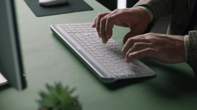 Slow motion close up of male hands typing on modern computer keyboard in office workspace, business technology and programming