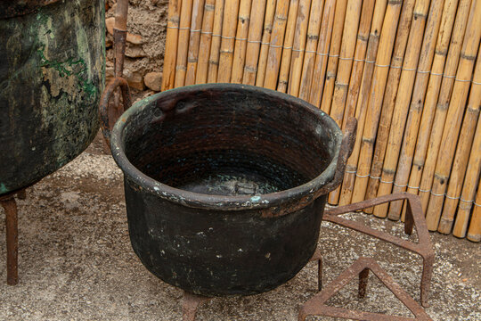 Copper pot with handles and green patina next to trivet stand and reed mats in traditional Spanish setting