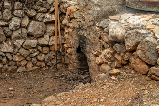 Traditional stone oven firebox with wooden tools by dry stone wall