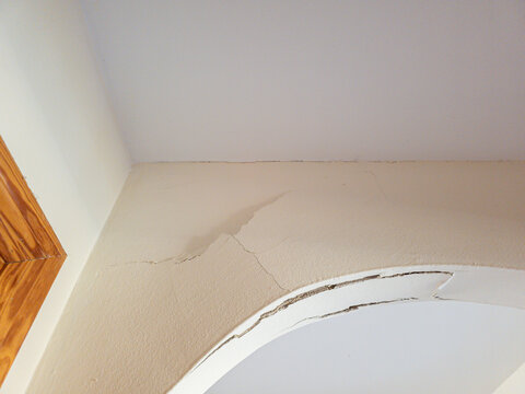 View of plaster damage and cracks on an interior arch caused by minor earthquakes and building movement in a residential space