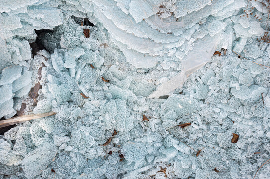 Shattered glass fragments and broken automotive safety glass pieces cover the ground in an abstract texture background