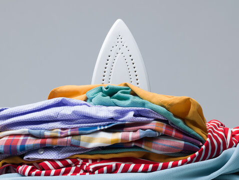 Steam Iron Soleplate Behind Stack of Folded Laundry