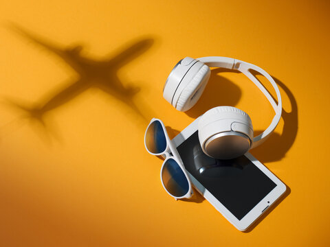 Modern Travel Tech with Headphones, Tablet and Airplane Shadow