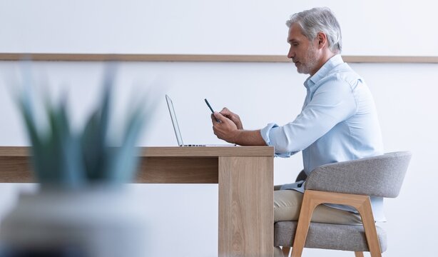 Happy middle-aged business man using smartphone