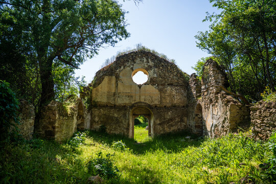View of the ruins of the St. George Monastery, featuring weathered stone walls, a circular window, and lush green vegetation in Viden, Stara Zagora, Bulgaria.