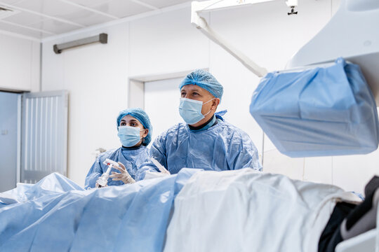 Medical team monitoring a patient during a catheter based procedure in a modern cardiac operating room.