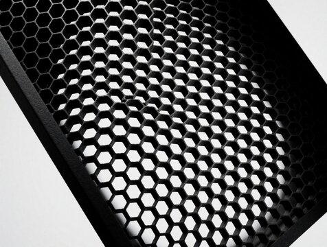 Black honeycomb grid light modifier for pro studio photography. Close up macro view shows hexagonal pattern, geometric texture of lighting equipment. Dark metal tool used to control light beam shape,