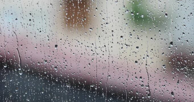 Water drops on the window during a heavy storm. Raindrops slowly slide down the glass surface.
