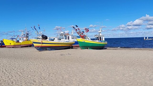 Kolorowe łodzie rybackie na piaszczystej plaży nad morzem pod błękitnym niebem