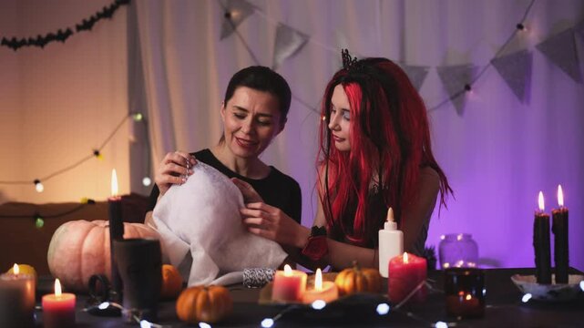 Mother Helps Daughter Create A Festive Halloween Atmosphere At Home By Making A Flying Ghost From A Balloon