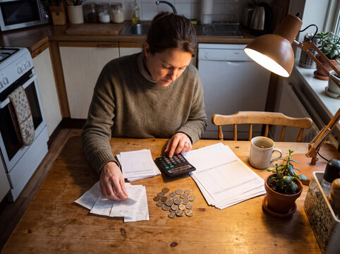 Woman Calculating Household Expenses and Budgeting at Kitchen Table