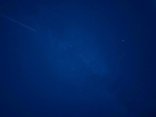 Fototapeta premium Cielo nocturno de color azul oscuro profundo salpicado de diminutas estrellas brillantes, transmitiendo serenidad, inmensidad y misterio cósmico.