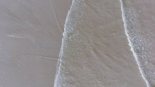 Waves gently crash onto soft, sunlit sand