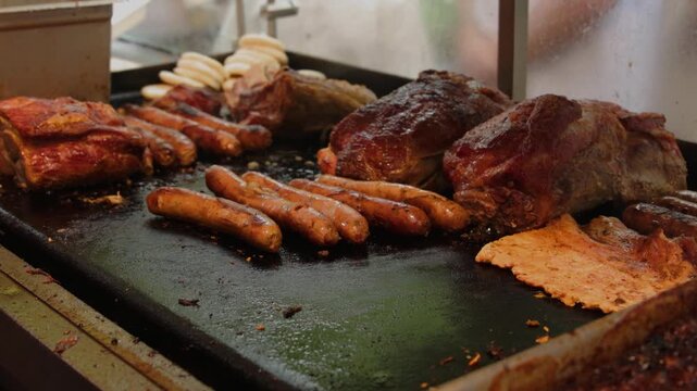 Assorted pork meat chorizo sausages and corn arepas grilling on flat metal griddle 60fps 4k